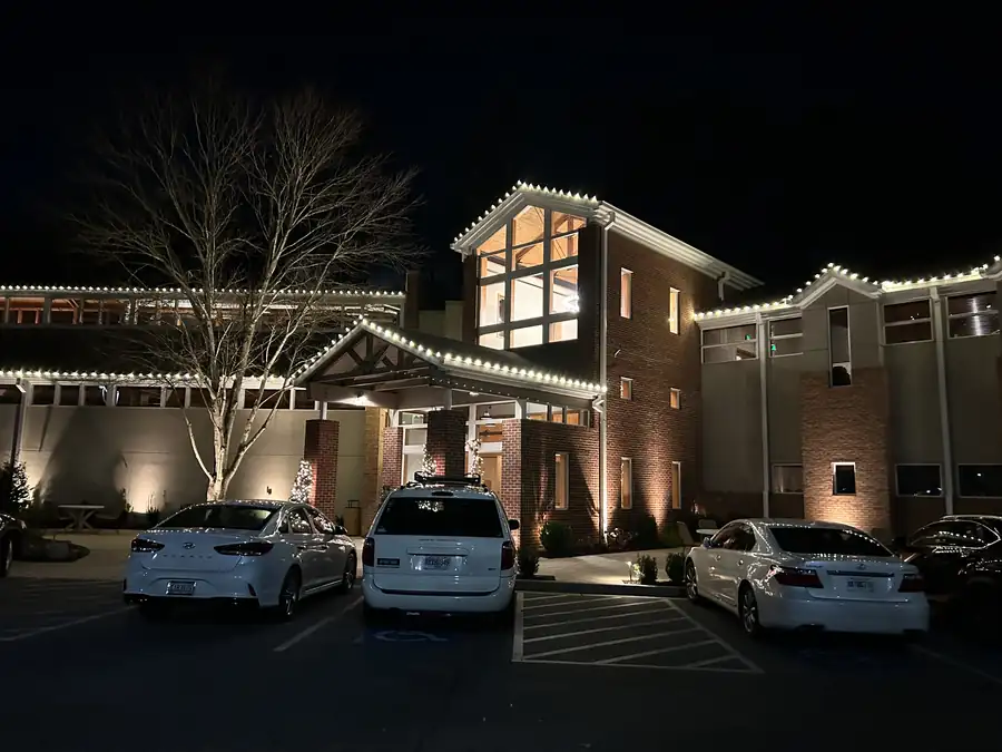 Large commercial property entrance holiday lighting with illuminated rooflines and entry approach