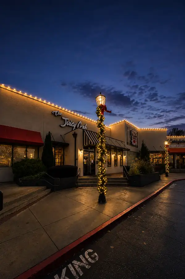 Commercial property nighttime holiday lighting with illuminated roofline and decorated lamp post