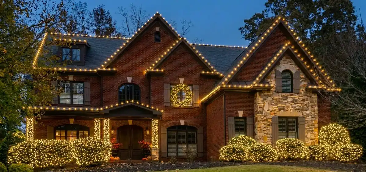 Full-home holiday lighting with warm roofline lights, wreaths and illuminated landscaping
