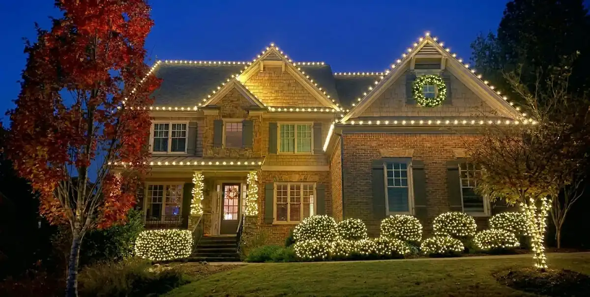 Residential Christmas lighting with illuminated shrubs, rooflines and front-yard landscaping