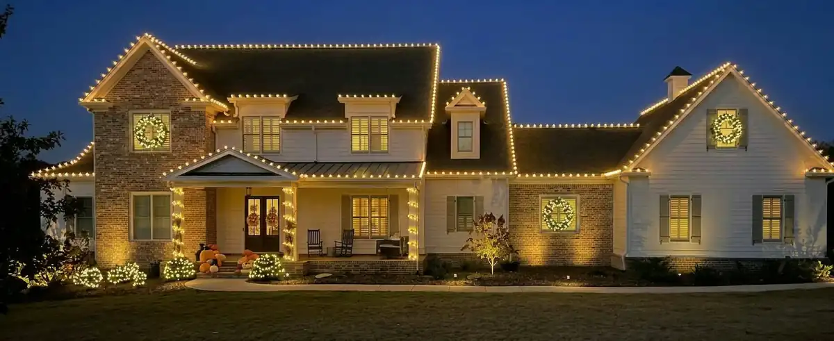 Premium home holiday lighting with warm roofline lights and decorative wreath accents