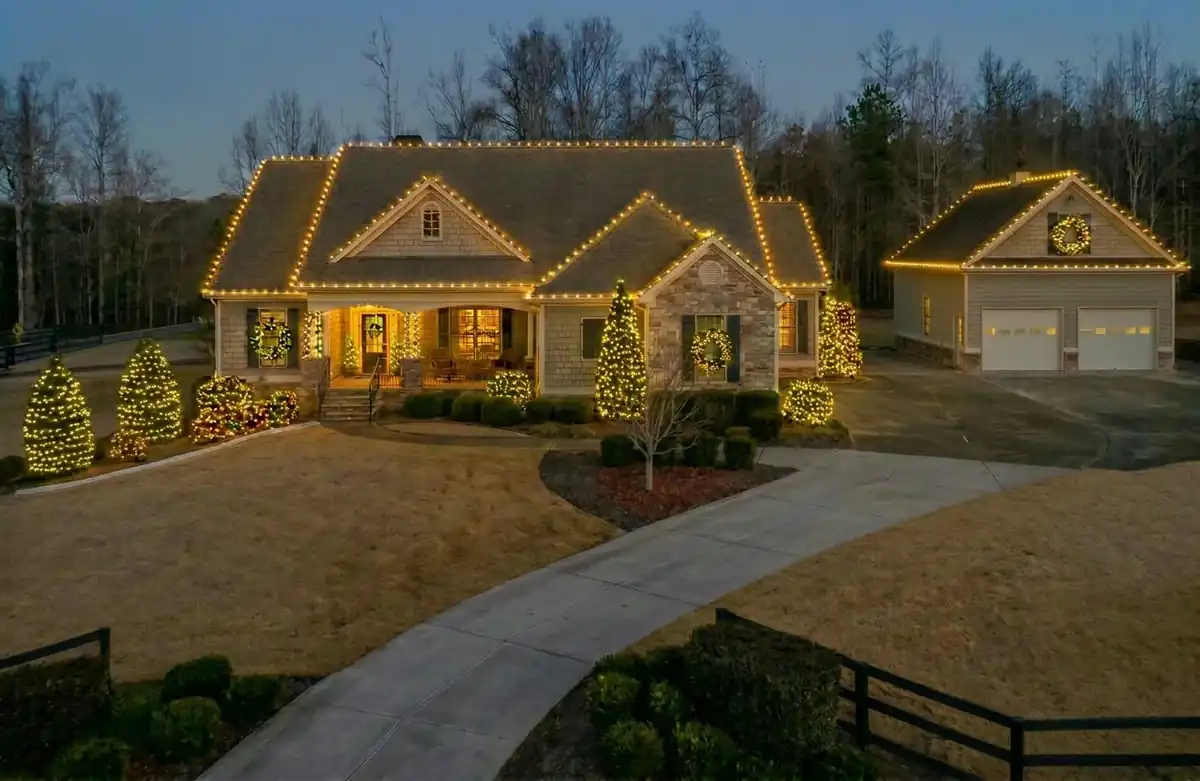 Residential property Christmas lighting with decorated trees, rooflines and detached garage accents