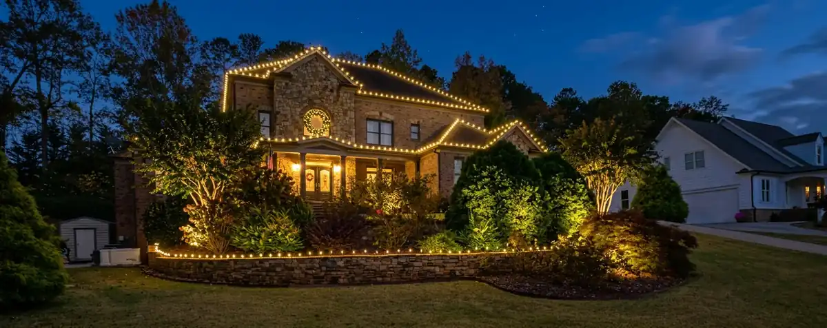 Wide residential Christmas light display with roofline and landscape illumination